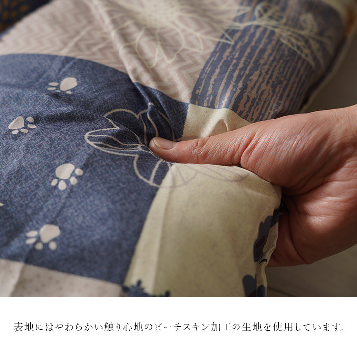 ピーチスキン加工を施したブルー系のこたつ掛け布団の表地を手でつまんだ様子