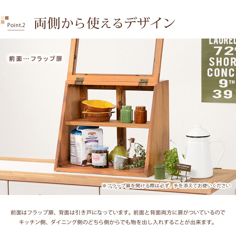 ナチュラル色の木製カウンター上ガラスケース、2段タイプの前面フラップ扉を開いた様子。上下の棚に食器や瓶、食品を収納した使用例